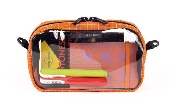 A Zest (pale orange) with white grid pattern (Halcyon) 3D Clear Organizer Cube filled with sundries.
